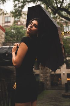 Stylish woman in black dress poses with an umbrella during a rainy day in Ottawa.
