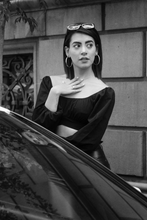 Free Black and white portrait of a woman posing confidently outdoors, exuding elegance and style. Stock Photo