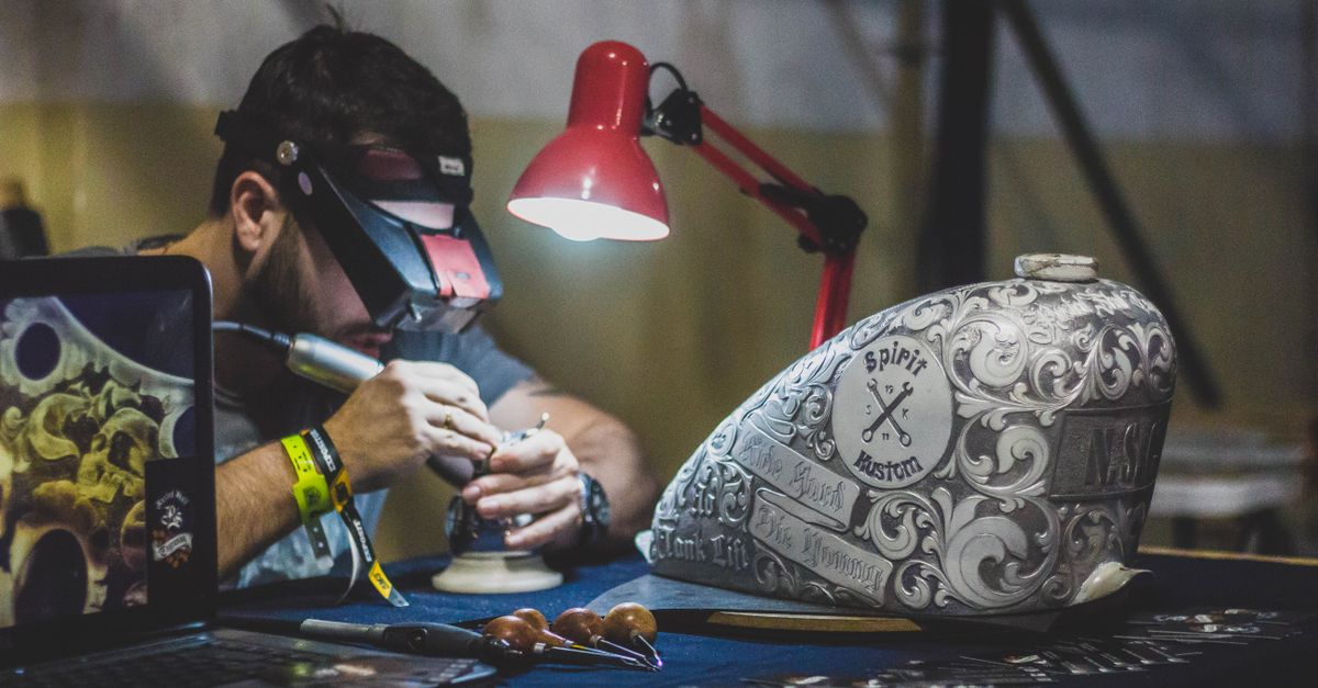 Artesano grabando con precisión una pieza metálica en un taller, ejemplo de fabricación personalizada de premios