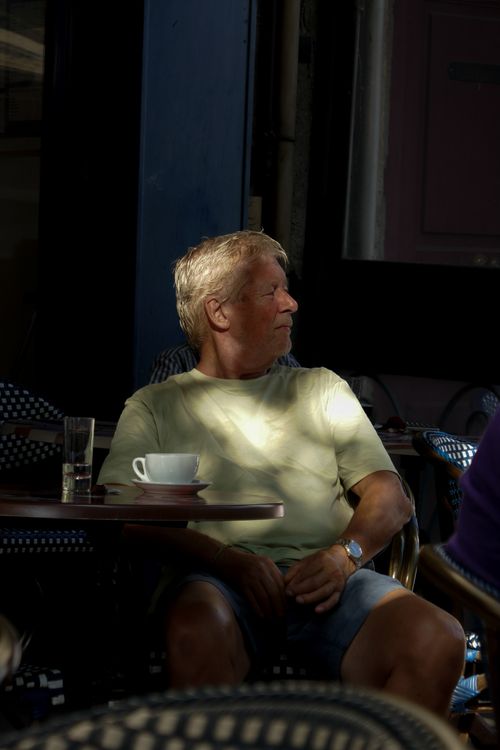 Free Elderly man enjoying a quiet moment at an outdoor café table with coffee. Stock Photo