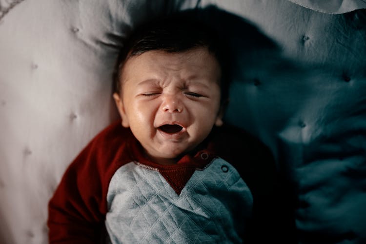 A Baby Crying While Lying On The Bed