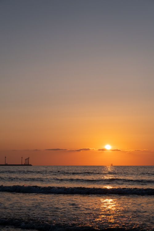 Free Peaceful ocean view during sunset with orange sky and calm waves. Stock Photo