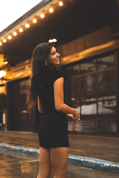 A Woman in Black Dress Standing on the Street