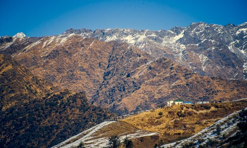Free Captivating view of snow-capped mountains and a solitary house under a clear blue sky. Stock Photo
