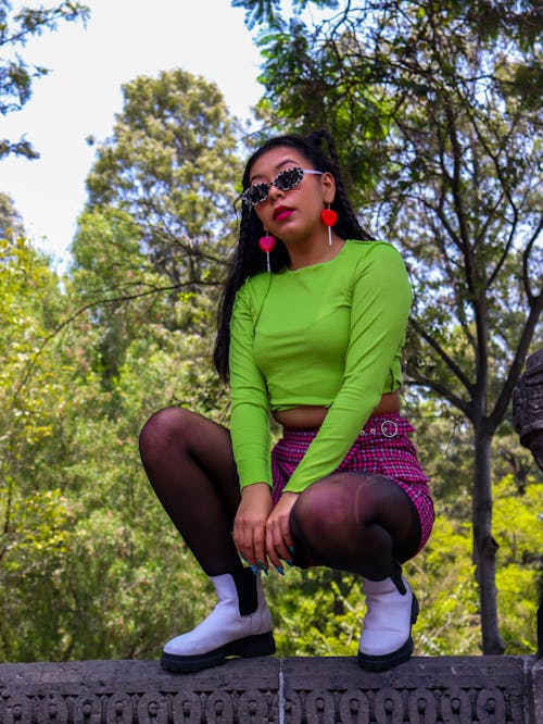A Woman in Green Long Sleeves and Plaid Skirt Wearing Sunglasses