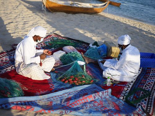 Free Two men preparing fishing nets on a beach in Doha, Qatar, showcasing traditional methods and teamwork. Stock Photo