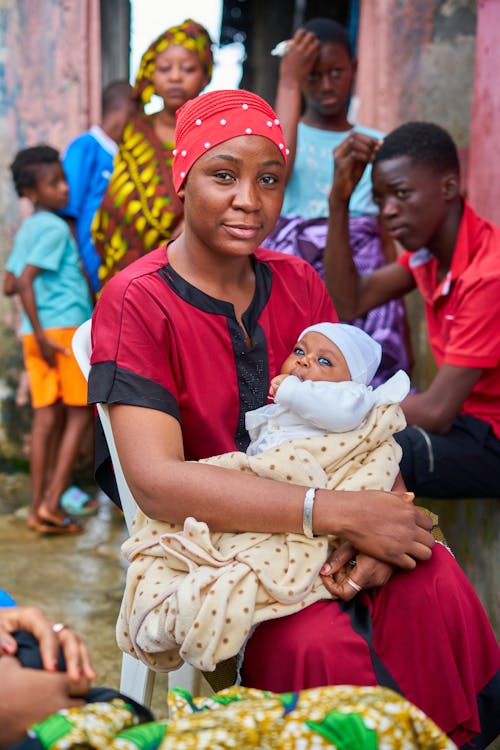 A Woman in Red Shirt Carrying Her Baby