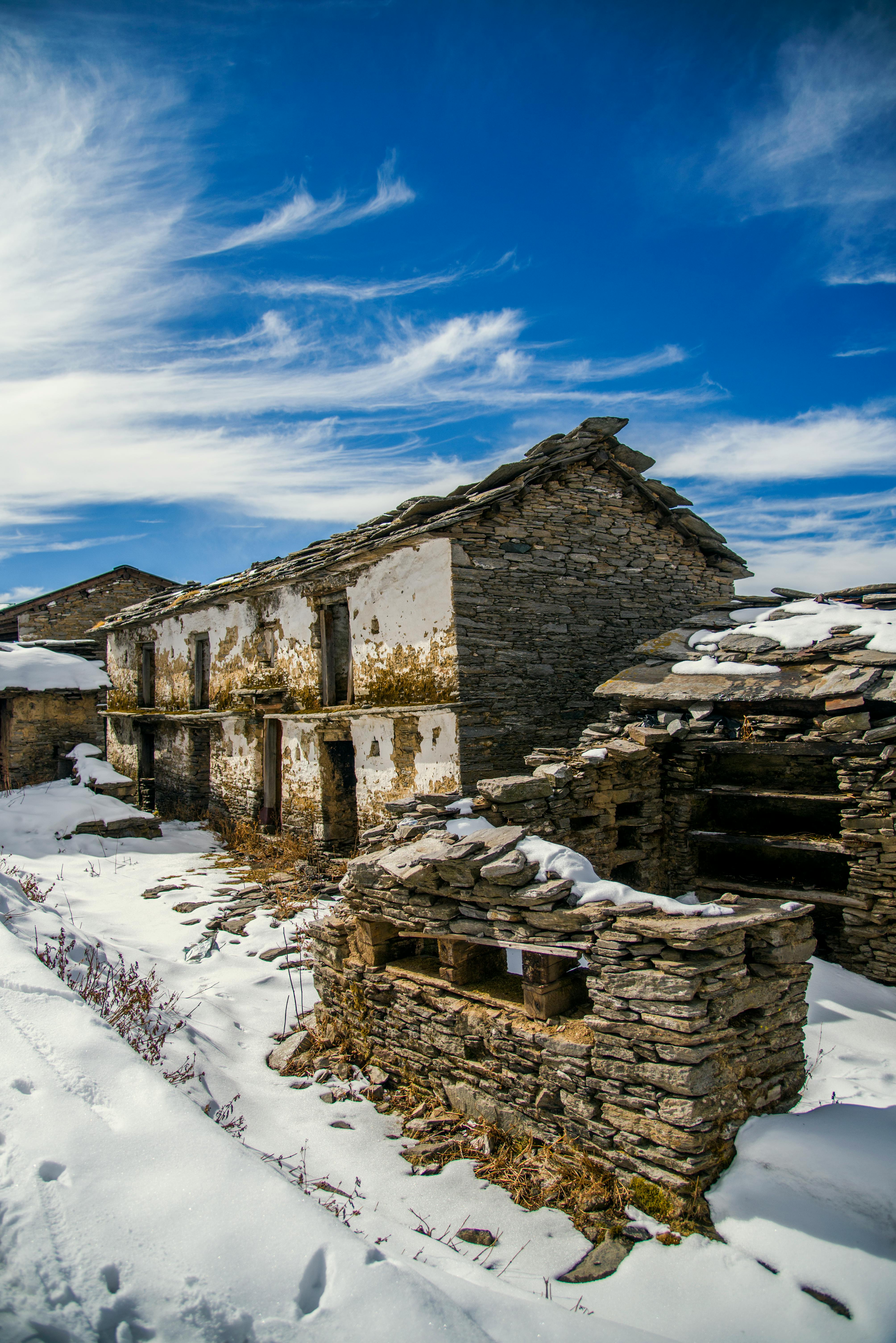 雪中废弃的石屋，映衬着清澈的蓝天，展现出宁静的冬季景观