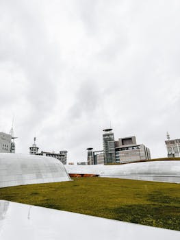A stunning cityscape featuring modern buildings and grassy rooftops under an overcast sky.