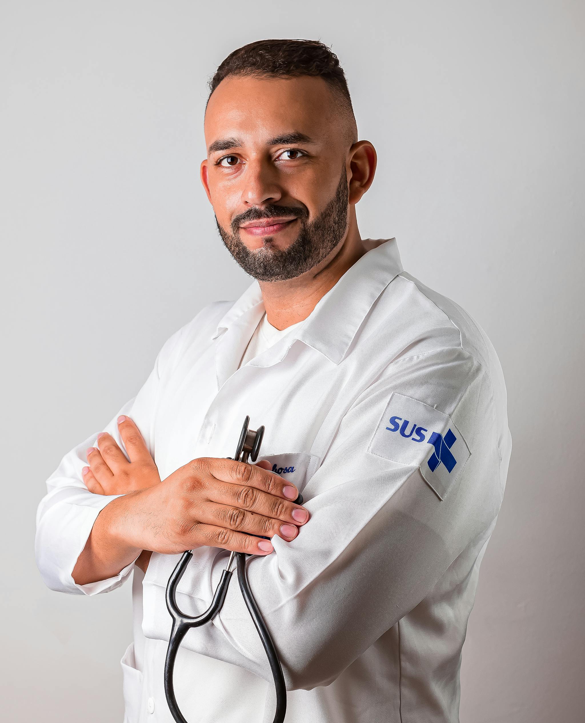 Portrait of a confident male doctor in a white coat with a stethoscope, posing in a studio setting.