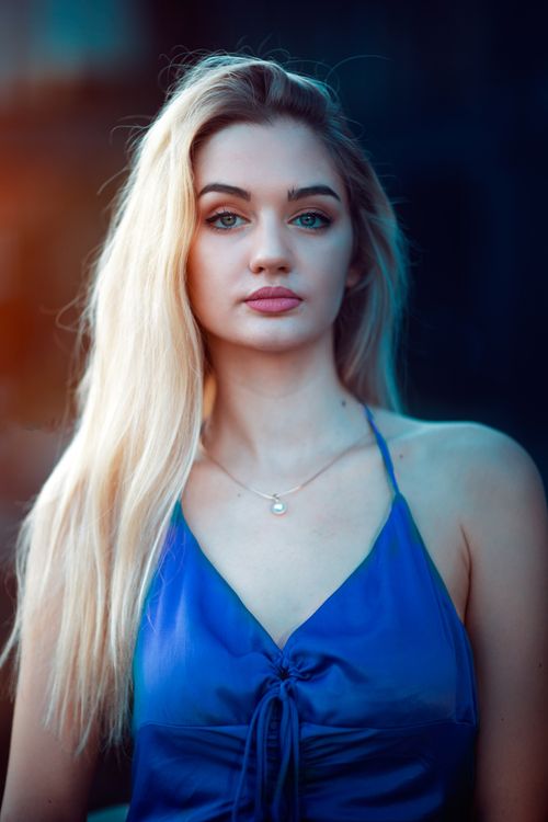Free Portrait of a beautiful blonde woman wearing a blue halterneck top, captured in natural light. Stock Photo