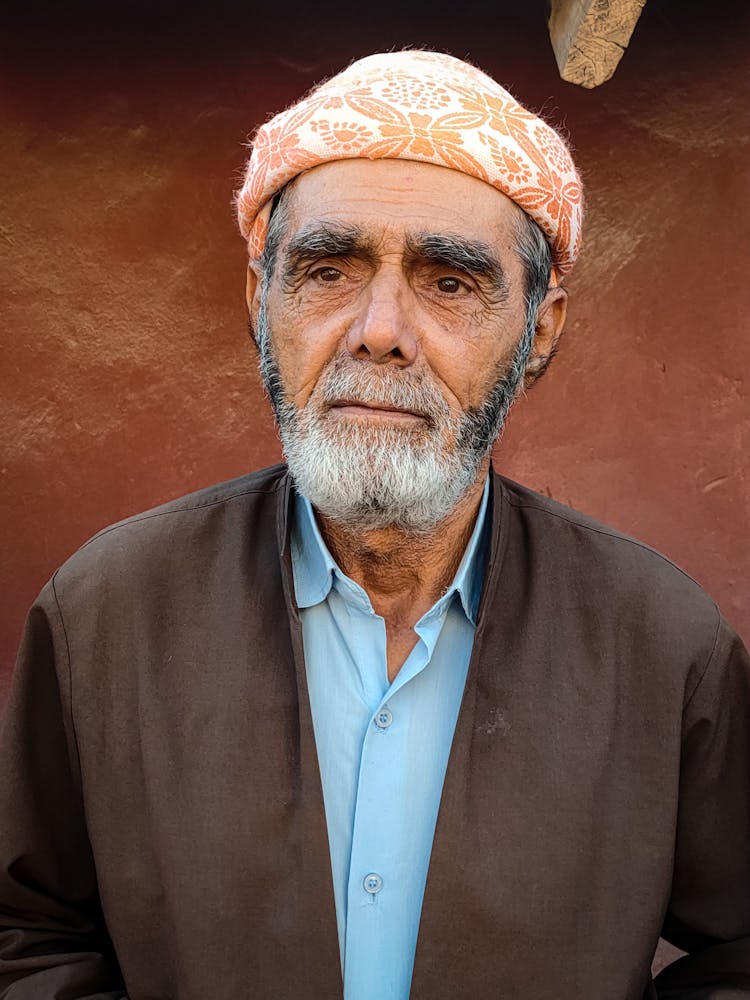 An Elderly Man In Orange Taqiyah Looking Afar