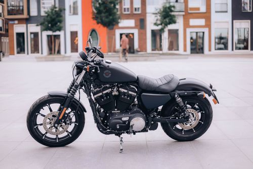 Free Black motorcycle parked on a modern urban street with contemporary buildings in the background. Stock Photo