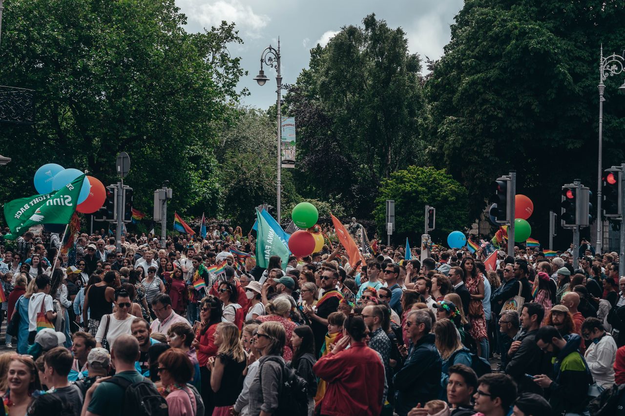 large crowd gathered for an outdoor celebration with balloons and flag