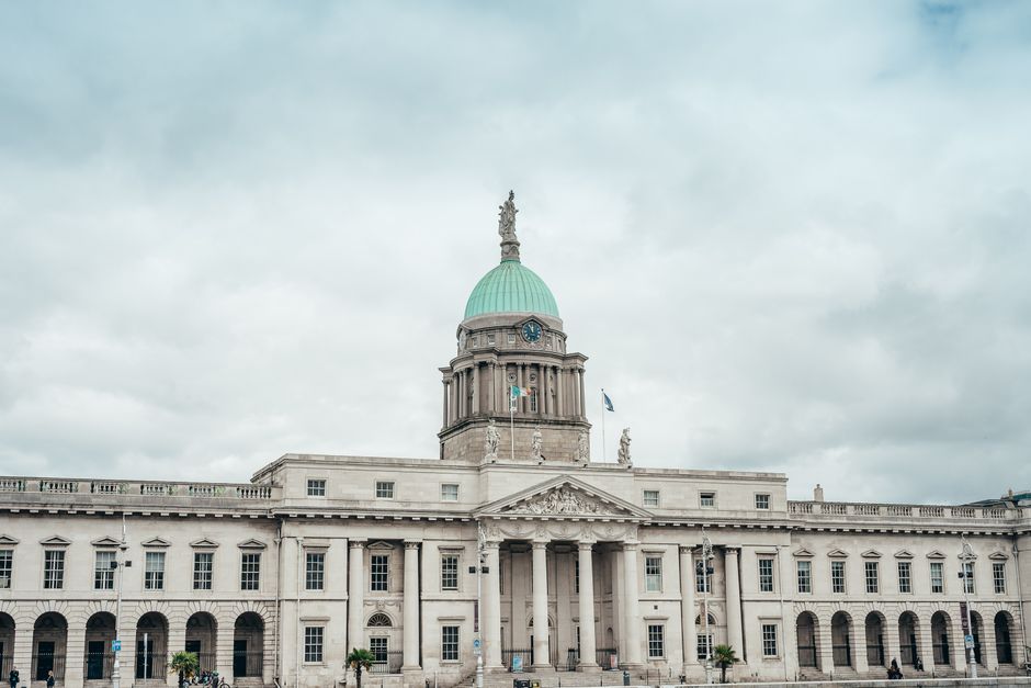 Elegant neoclassical Custom House facade under dramatic cloudy skies in Dublin, Ireland.