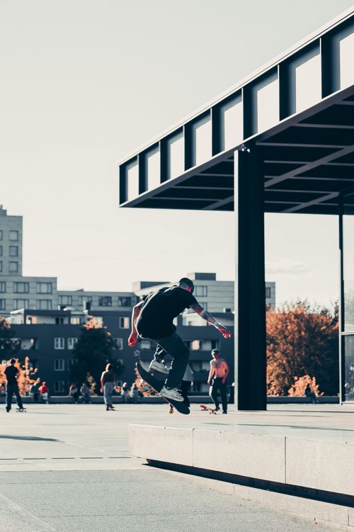 Free A dynamic skateboarder executes a mid-air trick in a sunlit Berlin skatepark. Stock Photo