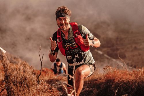 Free A smiling man in sportswear hiking energetically on a mountain trail showcasing adventure and determination. Stock Photo