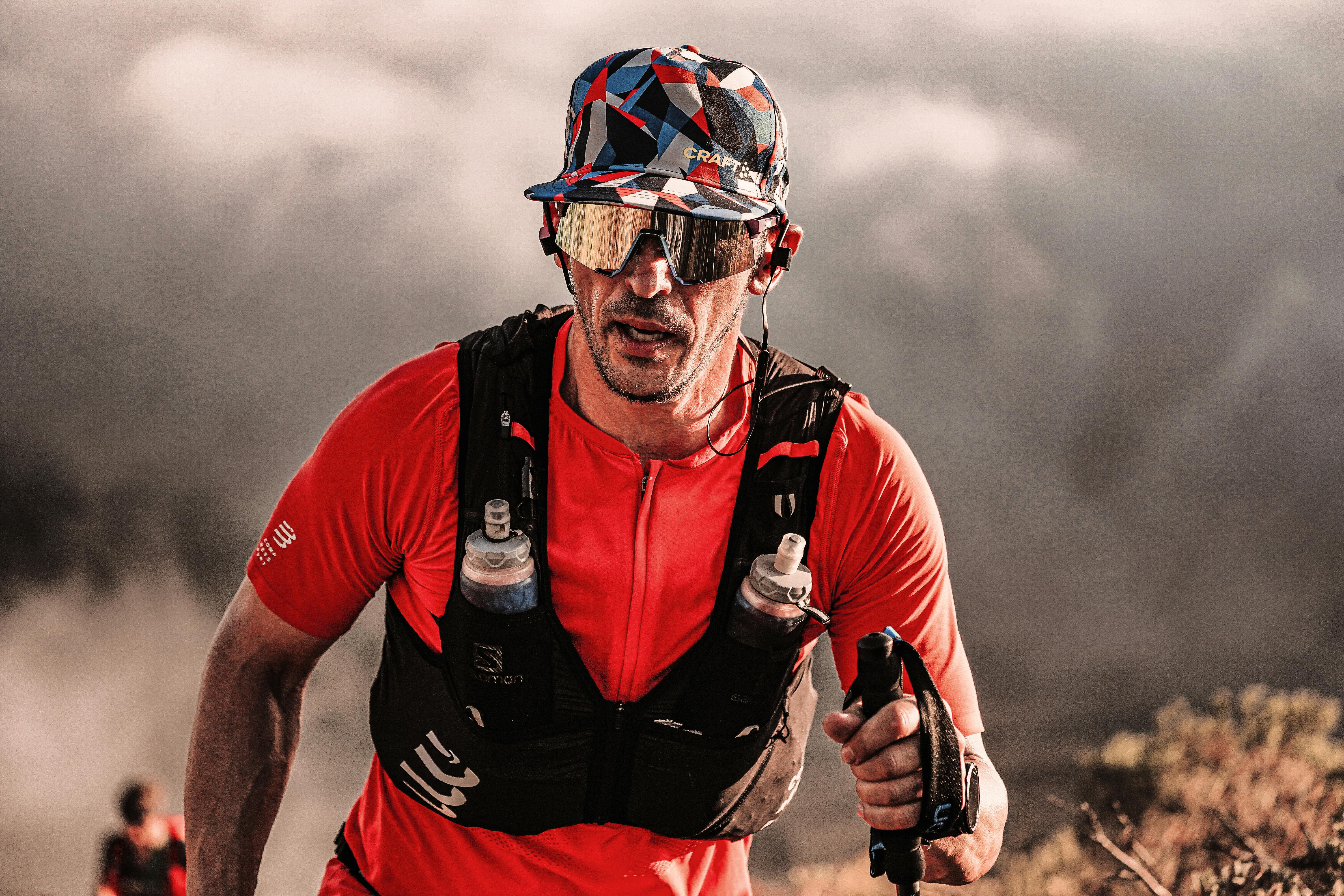 Focused runner in red sportswear conquering rugged terrain outdoors.