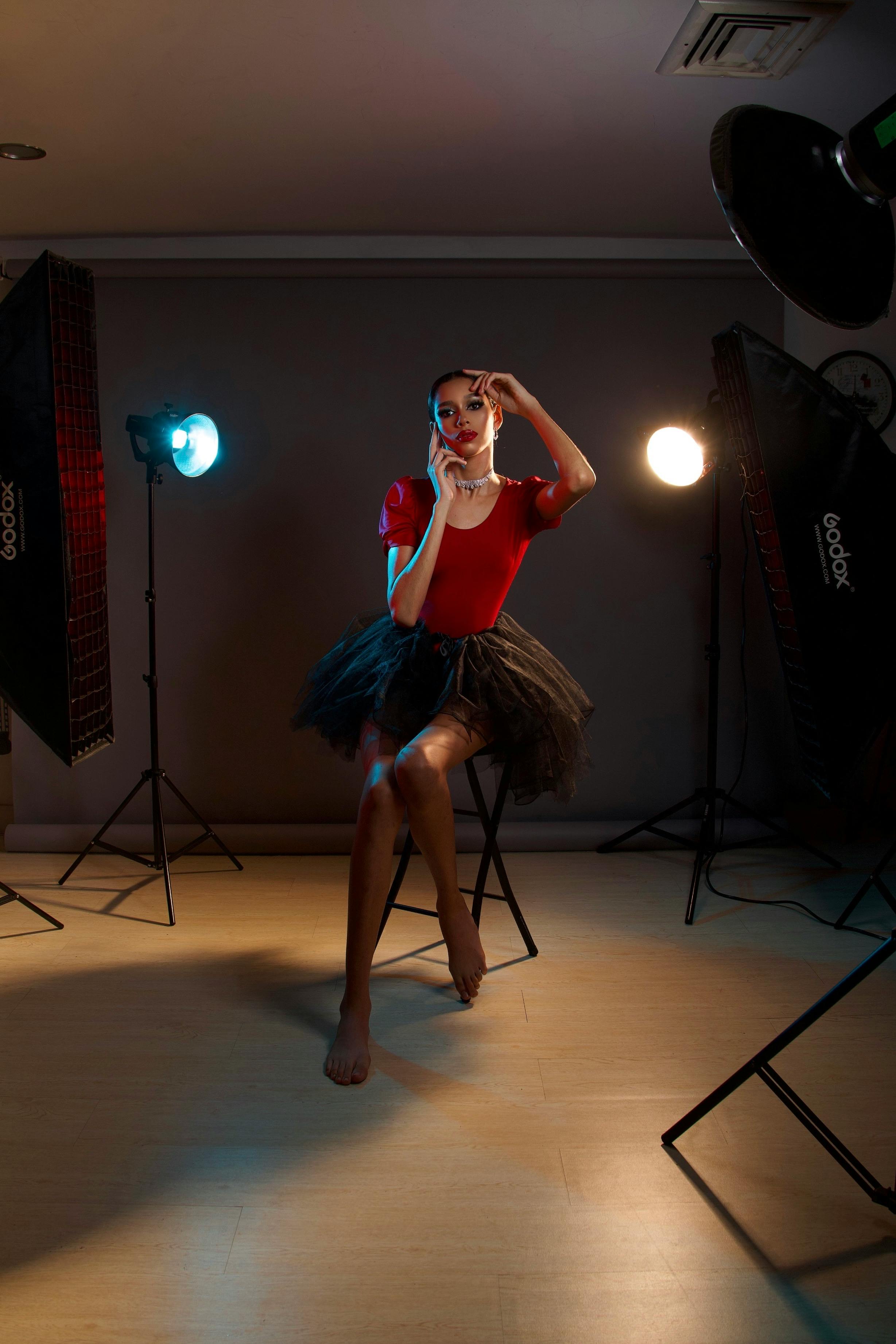 Gratis Seorang Wanita Berbaju Merah Duduk Di Kursi Sambil Berpose Di Depan Kamera Foto Stok