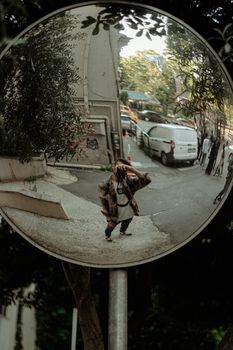 A street photographer's reflection captured in a convex mirror, urban scene.