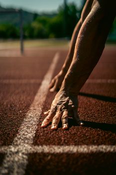 Close-up of an athlete's hands on a race track in Andenne, Belgium, ready for competition.
