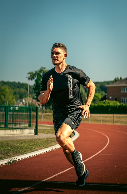 Man in Black Crew Neck T-shirt and Black Shorts Running on Field