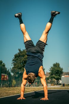 Athletic man doing a handstand on a sunny day in Belgique.