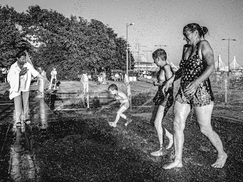 A Grayscale Photo of People Playing on Water while Raining