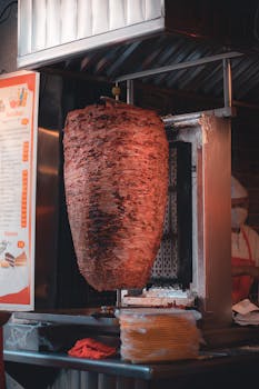 Delicious shawarma rotating on a vertical grill at a street food restaurant.