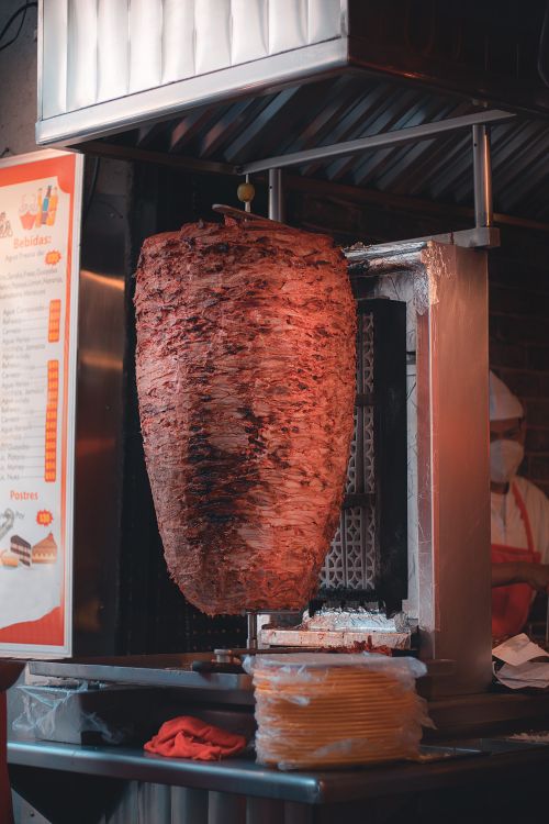 Free Delicious shawarma rotating on a vertical grill at a street food restaurant. Stock Photo