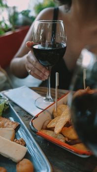 Atmospheric shot of a person holding wine, enjoying snacks at a table in İstanbul, Türkiye.