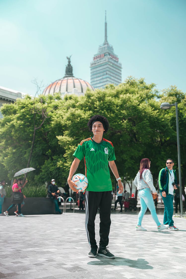 A Man In A Green Shirt Holding A Soccer Ball