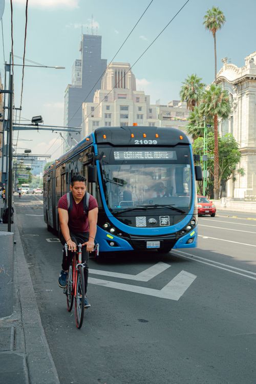 Cyclist Riding Behind Bus A Man Riding a Bike on the Road Near the Bus · Free Stock Photo