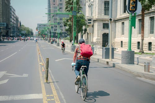 Man in Colorful Shirt Riding Bicycle on Road