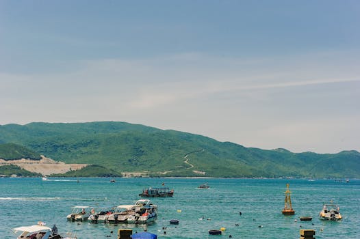 Tranquil view of boats floating near a lush green island under a clear blue sky.