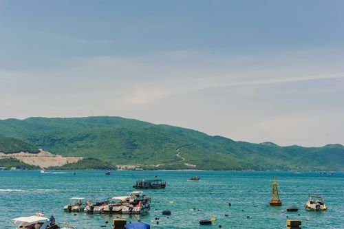 Free Tranquil view of boats floating near a lush green island under a clear blue sky. Stock Photo