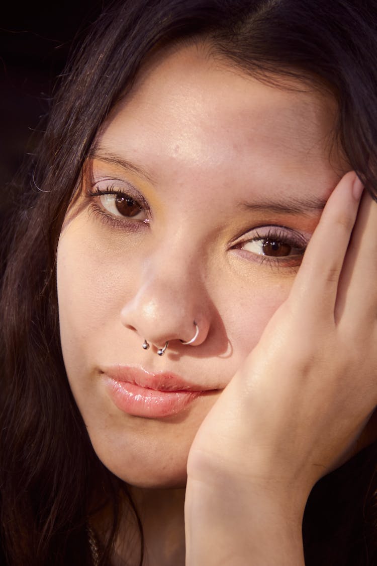 A Close-up Shot Of A Woman's Face With Nose Piercings