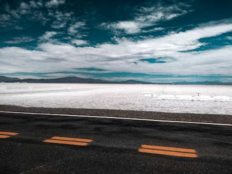 Breathtaking view of Salinas Grandes with cloudy sky and empty road near Jujuy, Argentina.