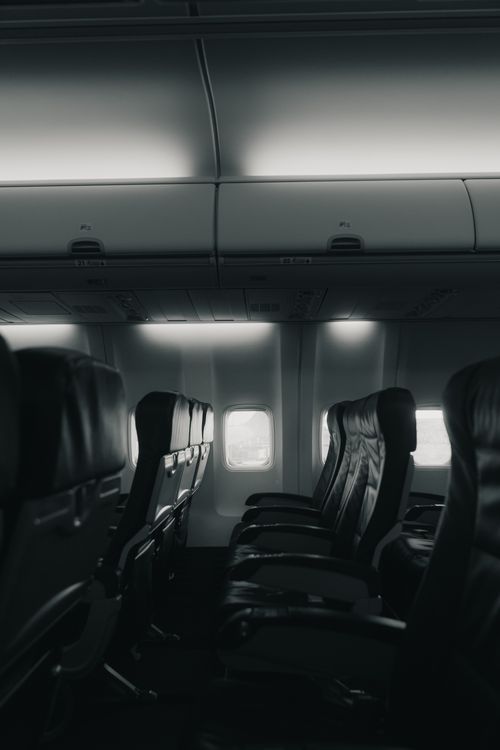 Free A moody grayscale shot of empty airplane seats capturing a quiet interior ambiance. Stock Photo