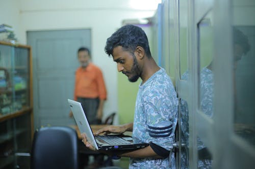 Man standing using laptop at work