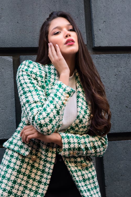 Woman in Green and White Checkered Coat Standing Beside Concrete Wall