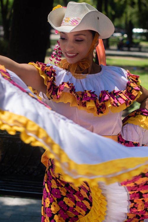 Free A woman happily dances in colorful traditional Mexican attire outdoors. Stock Photo
