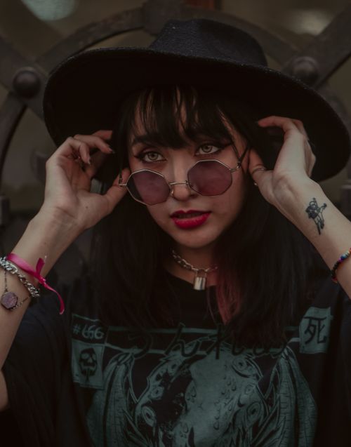 Free Edgy portrait of a woman with sunglasses and a wide-brimmed hat in a gothic style. Stock Photo