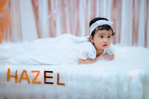 Free Baby in White Dress Lying on Bed Stock Photo