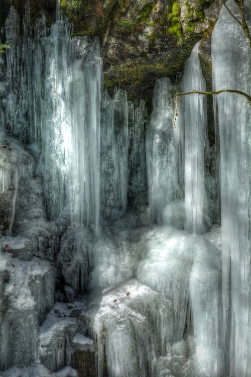 Free Close-up of frozen icicles cascading down a mossy rock in Slovakia. Stock Photo