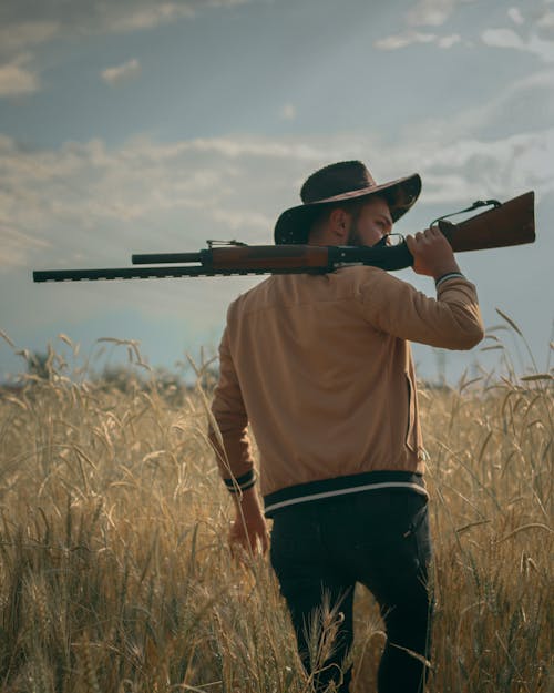 A Man in Brown Jacket Holding a Shotgun