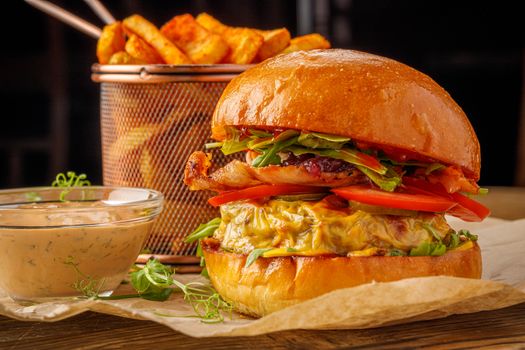Close-up of a juicy gourmet burger with fresh vegetables, cheese, and side of crispy fries.