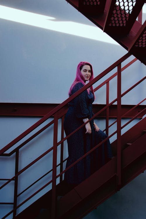 A Woman in Black Dress Walking on Metal Stairs