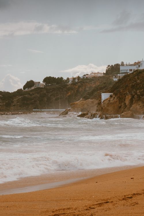Free Peaceful seaside scenery featuring cliffs and gentle waves on a sandy beach. Stock Photo
