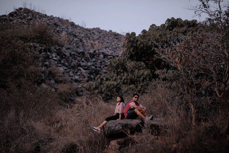 Woman And Man Sitting Among Bushes And Trees